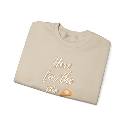 A beige crewneck sweatshirt folded neatly on a white background, featuring the text 'Here for the pie' in a light tan script with a slice of pumpkin pie graphic.