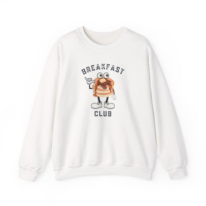 A white crewneck sweatshirt featuring a cartoon graphic of a breakfast stack of pancakes character with the text 'BREAKFAST CLUB' printed on the front, displayed against a clean white background.