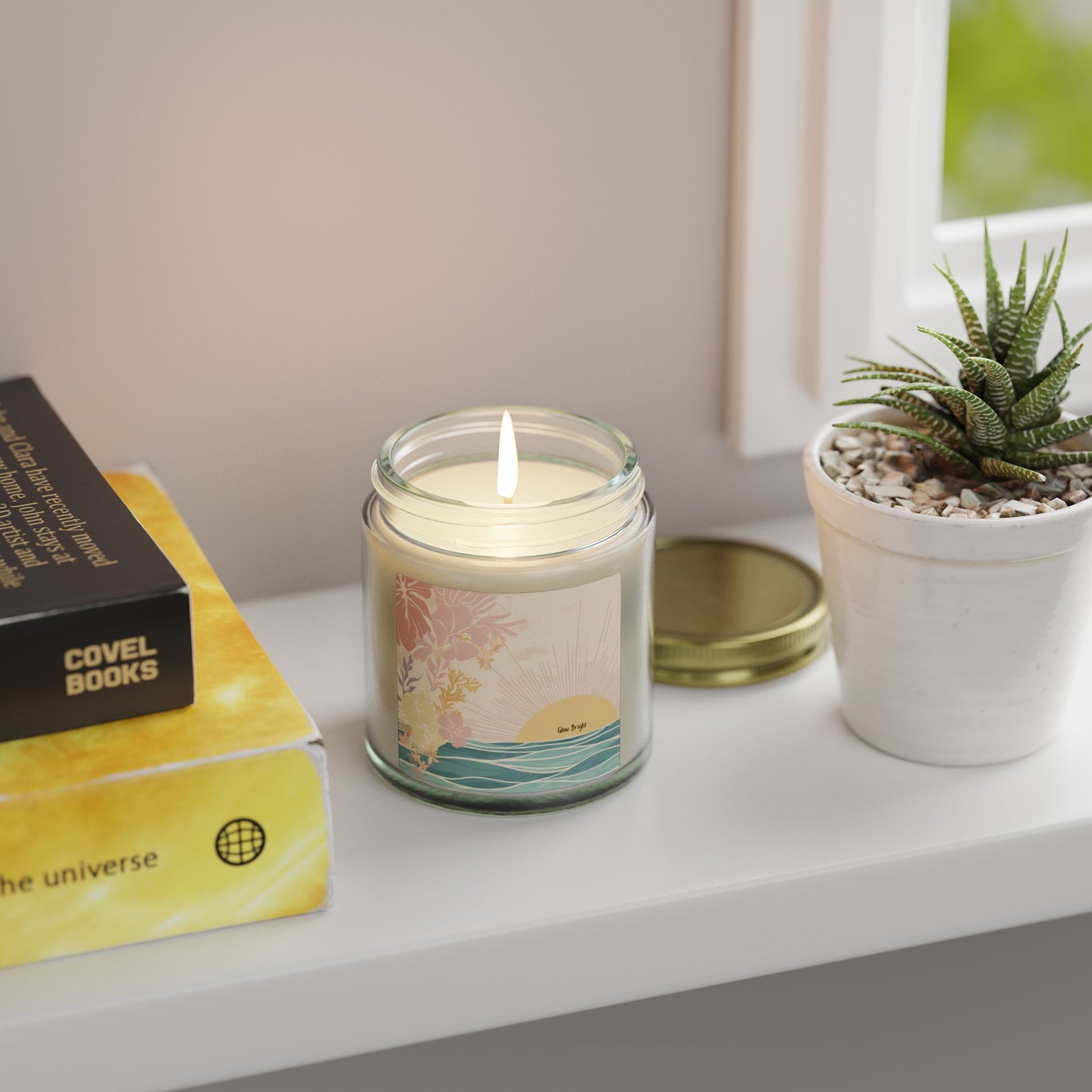 Candle labeled 'Glow Bright' on a shelf with books and a plant