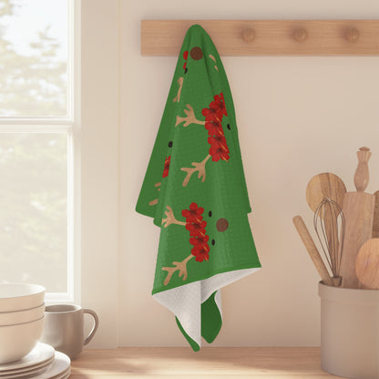Green Reindeer and Rudolph holiday kitchen towel with red nose design hanging off a wood peg on a kitchen wall
