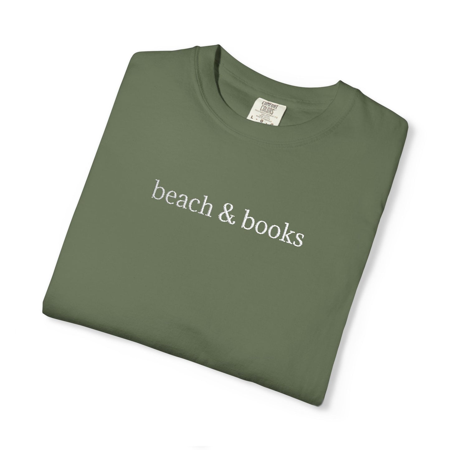 A folded green comfort colors tee with 'beach & books' embroidered in white