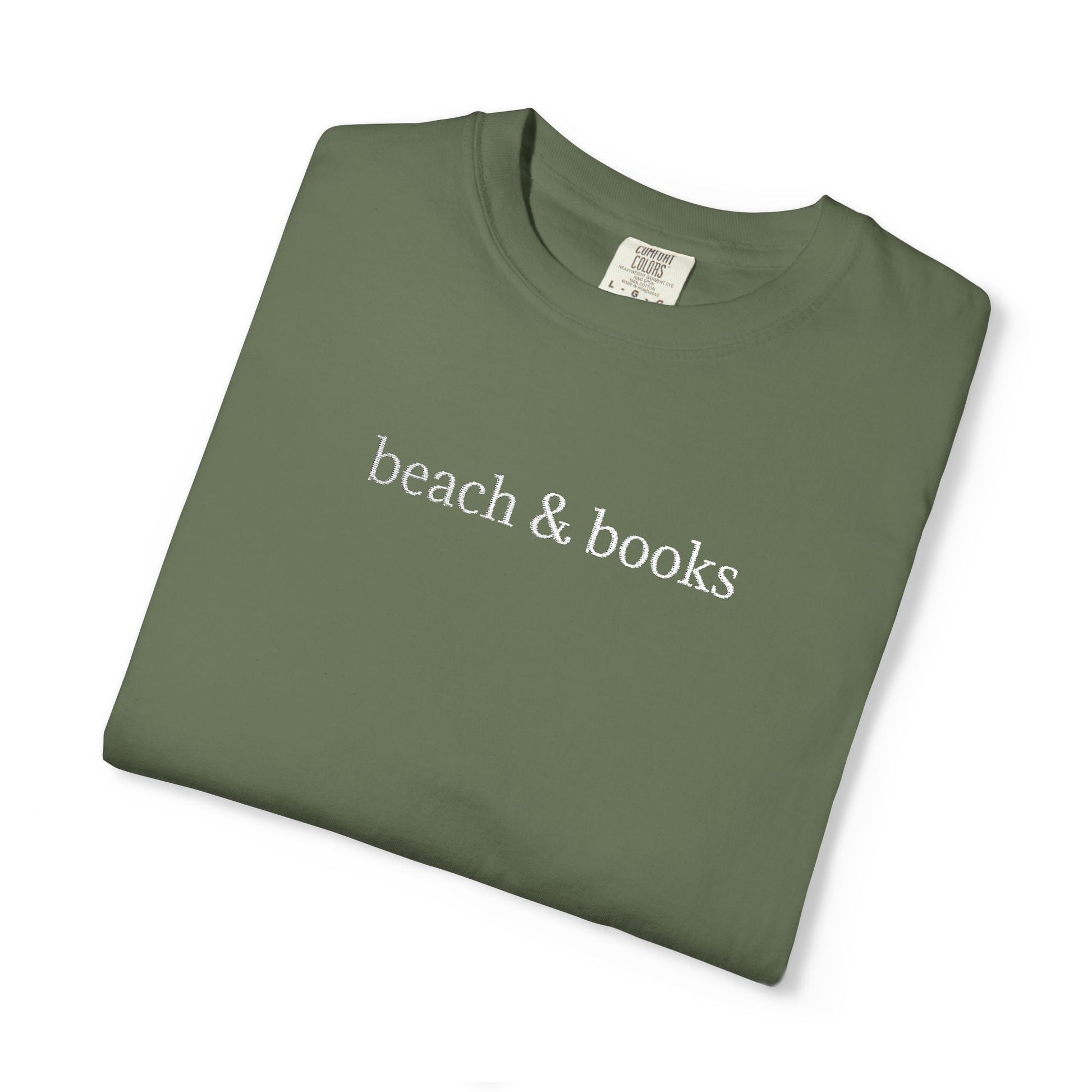 A folded green comfort colors tee with 'beach & books' embroidered in white