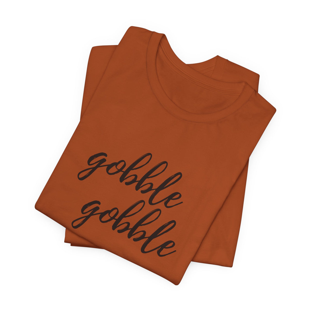 A folded rust t-shirt with the phrase 'gobble gobble' printed in black cursive script across the front, displayed on a clean white background.