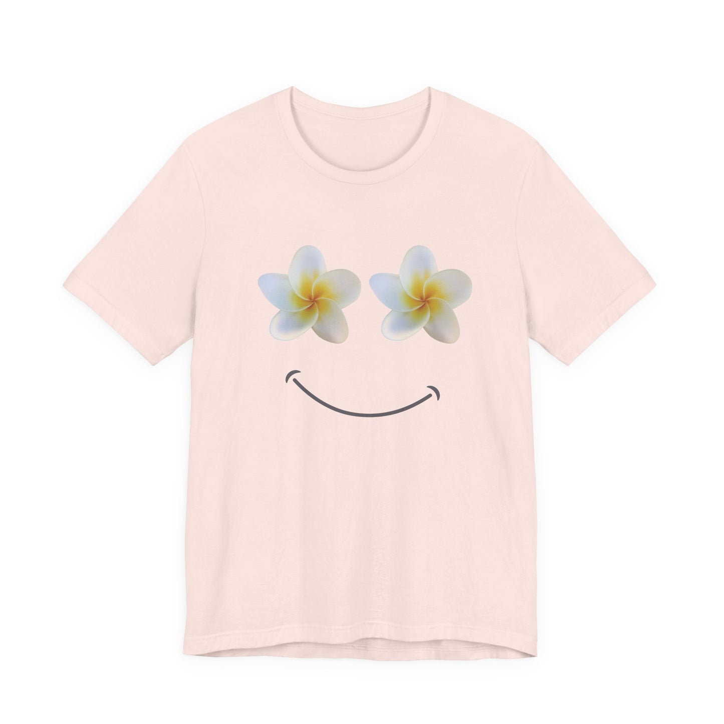 A light pink short-sleeve crewneck t-shirt featuring a graphic of two white plumeria flowers with yellow centers as eyes and a simple black smiley curve below, displayed on a clean white background.