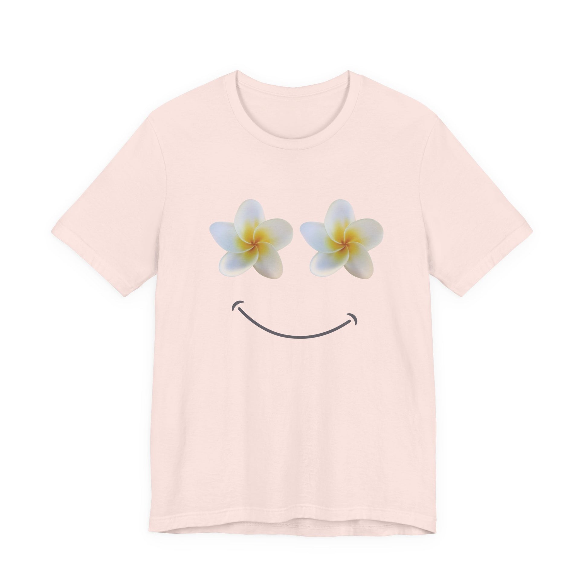 A light pink short-sleeve crewneck t-shirt featuring a graphic of two white plumeria flowers with yellow centers as eyes and a simple black smiley curve below, displayed on a clean white background.