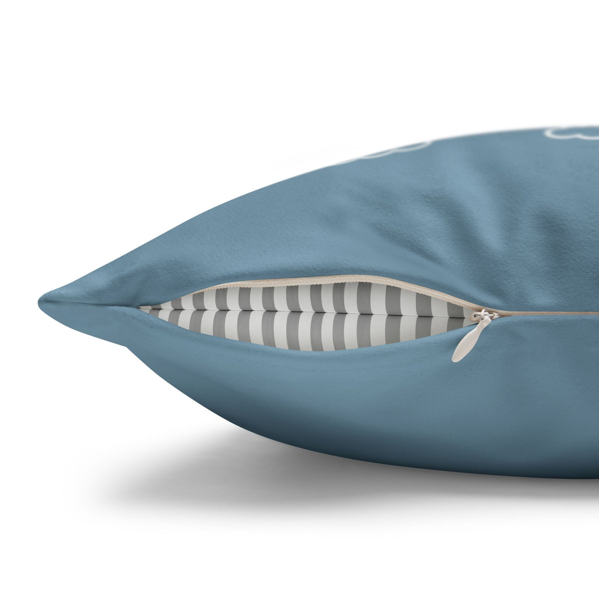 A close-up of a blue throw pillow with a partially unzipped front, revealing a gray and white striped interior cushion layer, on a white background.