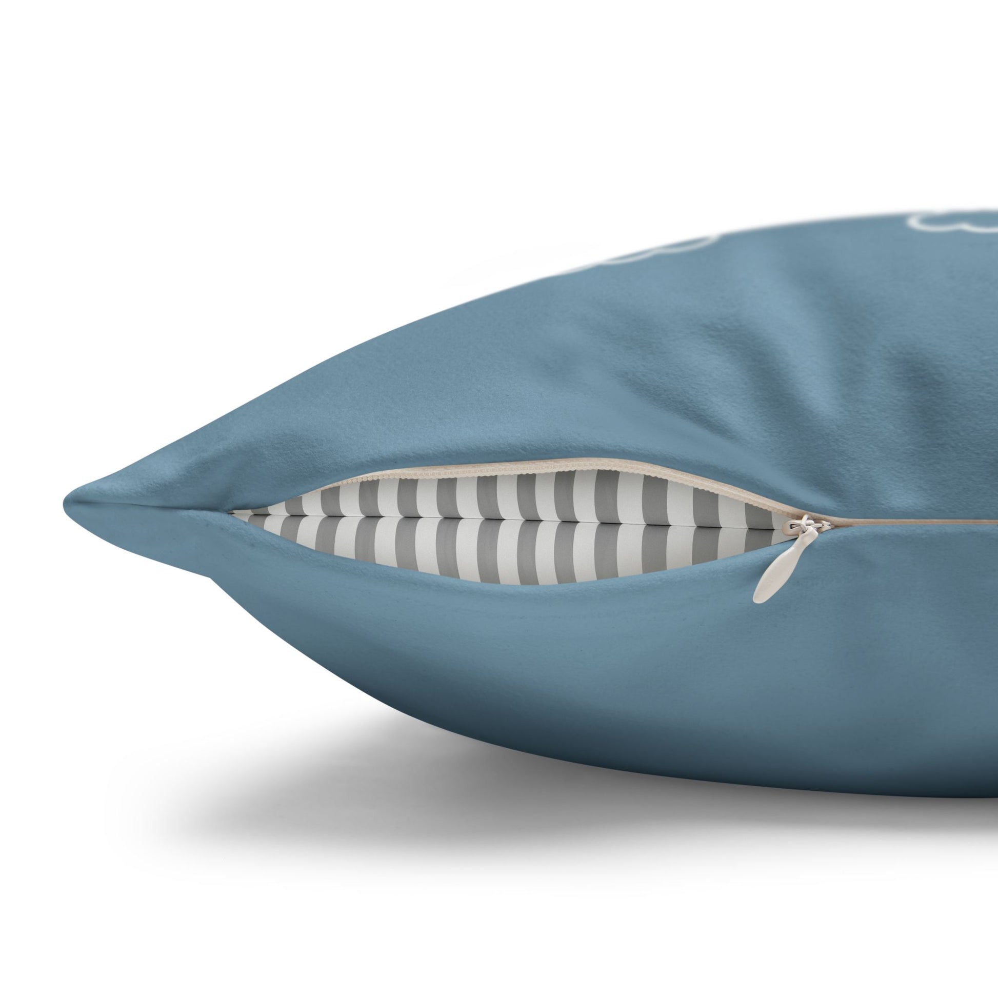 A close-up of a blue throw pillow with a partially unzipped front, revealing a gray and white striped interior cushion layer, on a white background.