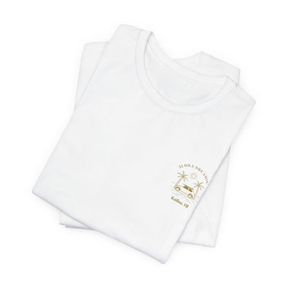 A folded white short-sleeve t-shirt shown from the front, featuring a gold-colored retro graphic of a classic car between two palm trees with the text 'ALOHA DREAMIN'' and 'Kailua, HI' on the left chest.