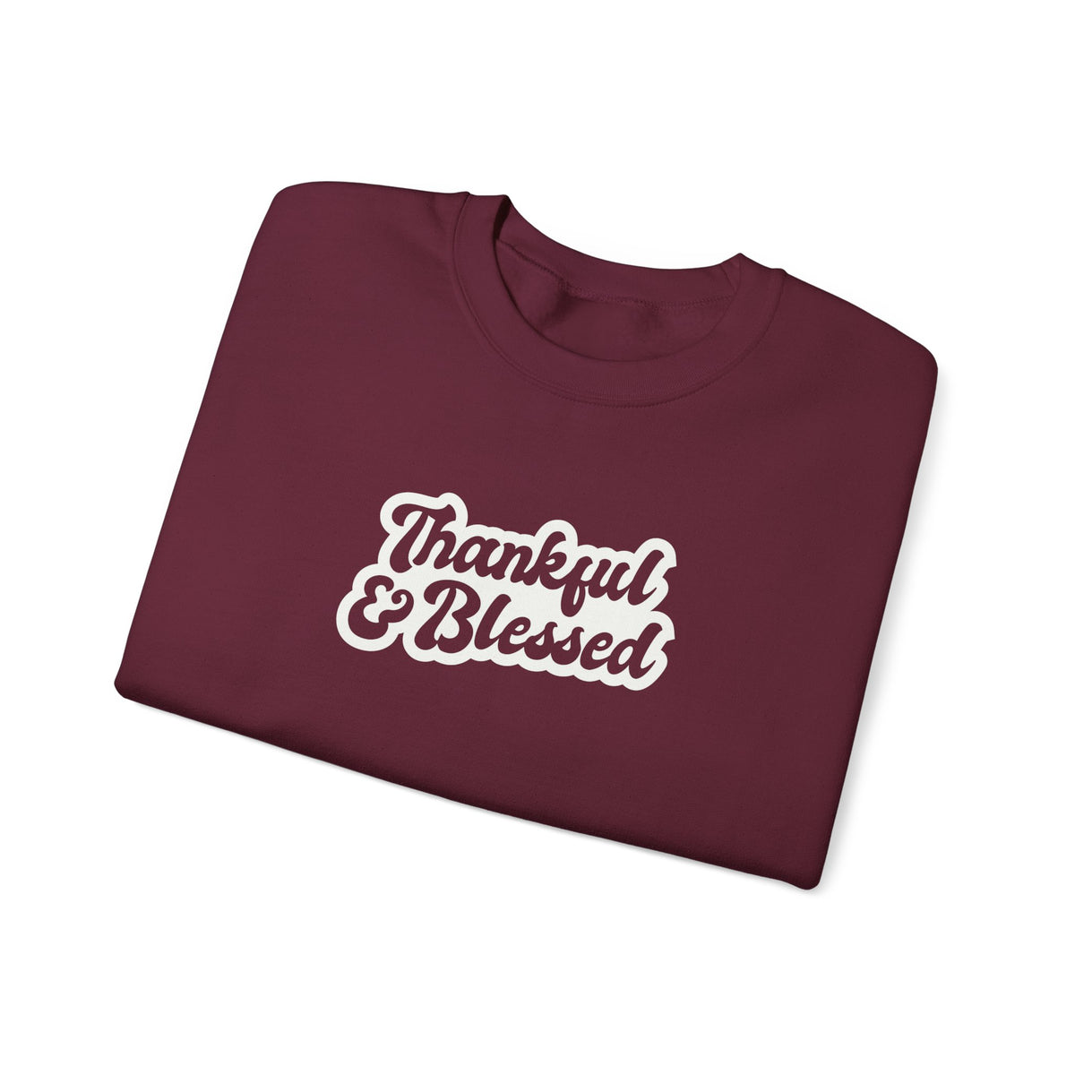 A folded maroon crewneck sweatshirt with 'Thankful & Blessed' printed in white script with a brown outline on the front, set against a plain white background.