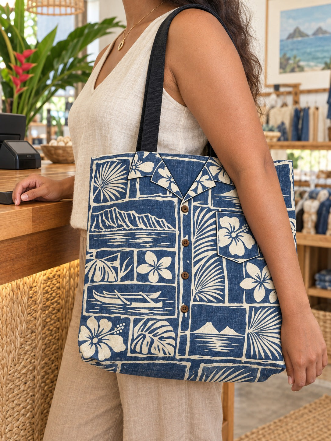 Indigo tote at checkout: Woman carrying an indigo and cream vintage aloha shirt tote with Hawaiian floral, canoe and island scenes at a shop counter.