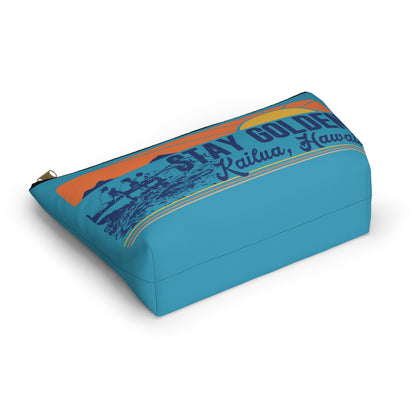 A rectangular zippered pouch in bright turquoise blue, featuring a retro-style graphic print with the text 'STAY GOLDEN Kailua, Hawaii' and a sunset motif in orange, yellow, and dark blue, shown on a clean white background.