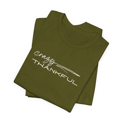 A folded olive Crazy Thankful graphic t-shirt by Global Village Kailua