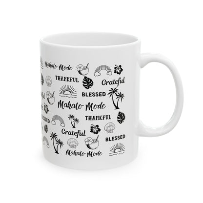 A white ceramic mug with a black tropical-themed print featuring the words 'Mahalo Mode', 'Grateful', and 'Blessed' alongside palm trees, monstera leaves, hibiscus flowers, and sun motifs, shown on a plain white background.