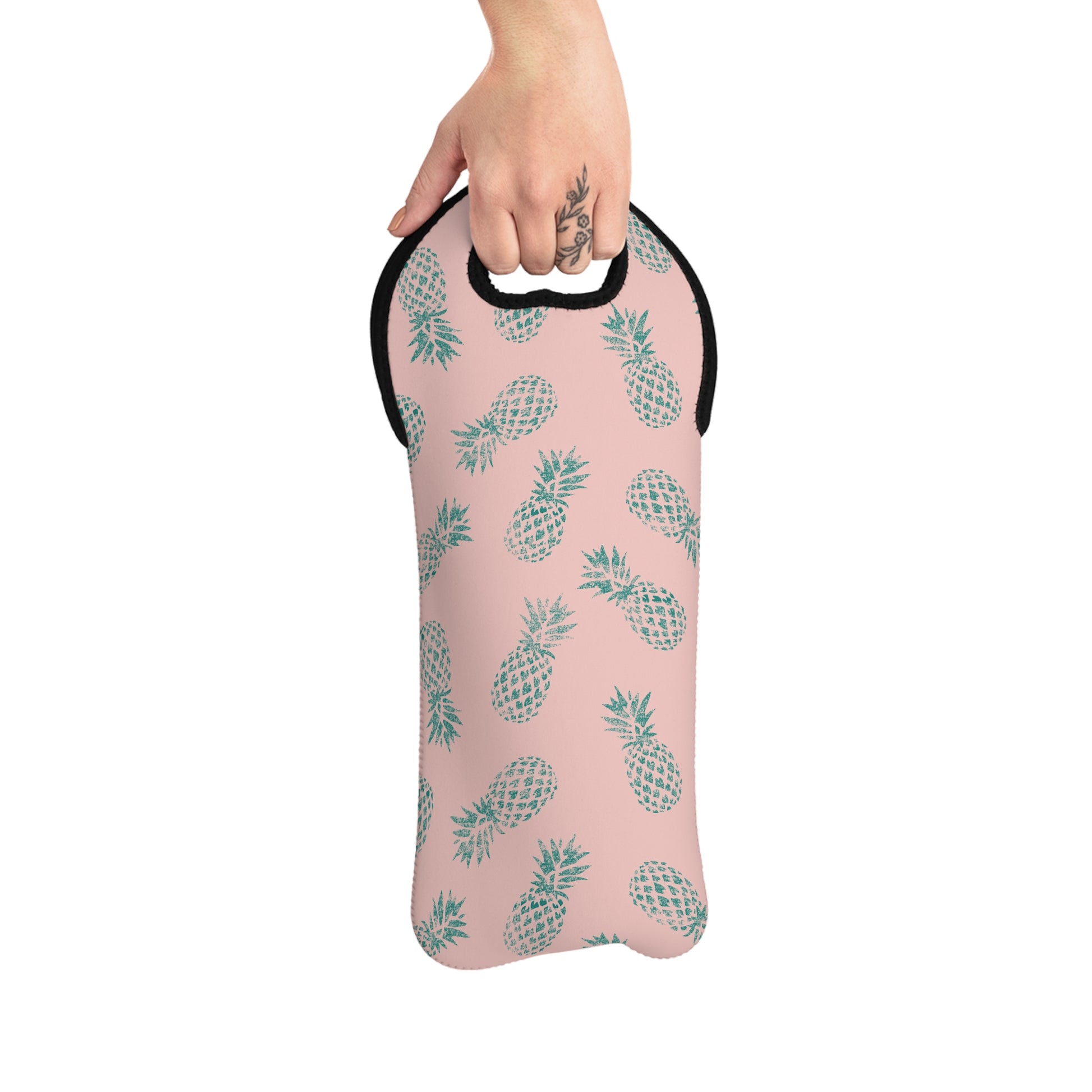 A pink neoprene wine tote featuring a repeating pattern of teal pineapples, with a black trim and a cutout handle at the top, shown on a plain white background.