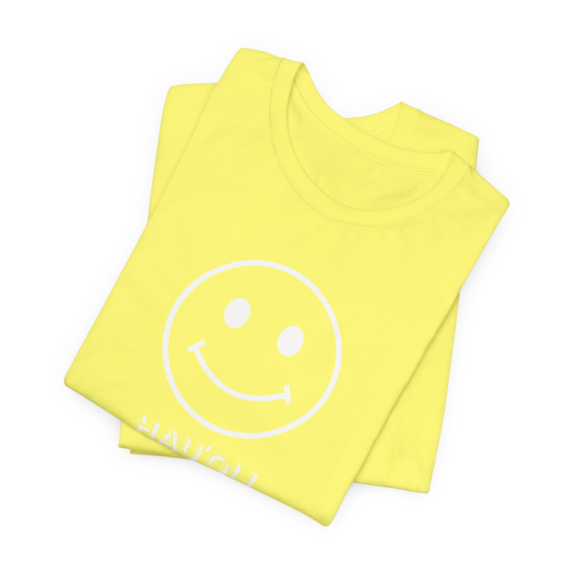 A folded bright yellow t-shirt with a white smiley face graphic and the word 'HAUʻOLI HAPPY' printed in white near the bottom, displayed on a clean white background.