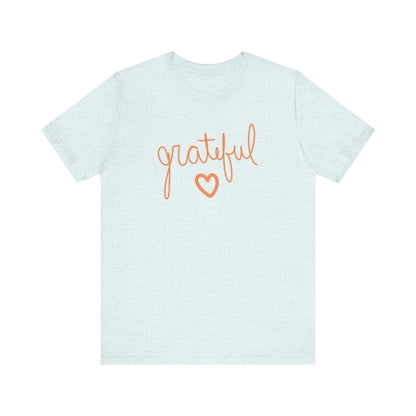A light blue short-sleeve t-shirt with the word 'grateful' written in orange cursive across the chest, with a matching orange heart outline underneath.