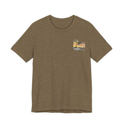 A heather olive short-sleeve t-shirt with a vintage-style graphic on the front left chest depicting two palm trees against a yellow and orange sunset, with the text 'ná makulua' and 'Kailua, Hawaii!' printed below.