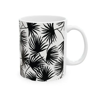 A white ceramic mug featuring a bold black palm leaf pattern, shown against a plain white background.