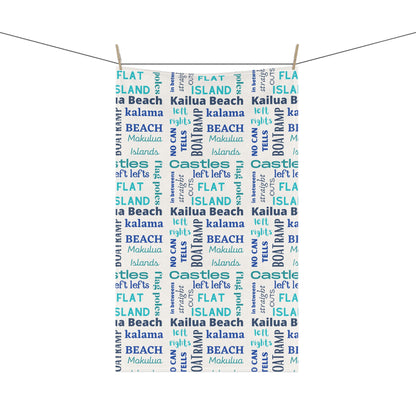 A tea towel featuring a repeating pattern of words like 'FLAT ISLAND', 'CASTLES', 'KALAMA BEACH', 'Kailua Beach', 'BOAT RAMP', and 'MOKOLUA ISLANDS' in blue, teal, and navy on a white background.