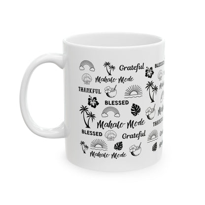 A white ceramic mug with a black tropical-themed print featuring palm trees, hibiscus flowers, monstera leaves, and words like 'Grateful', 'BLESSED', and 'Mahalo -Mode' on a plain white background.