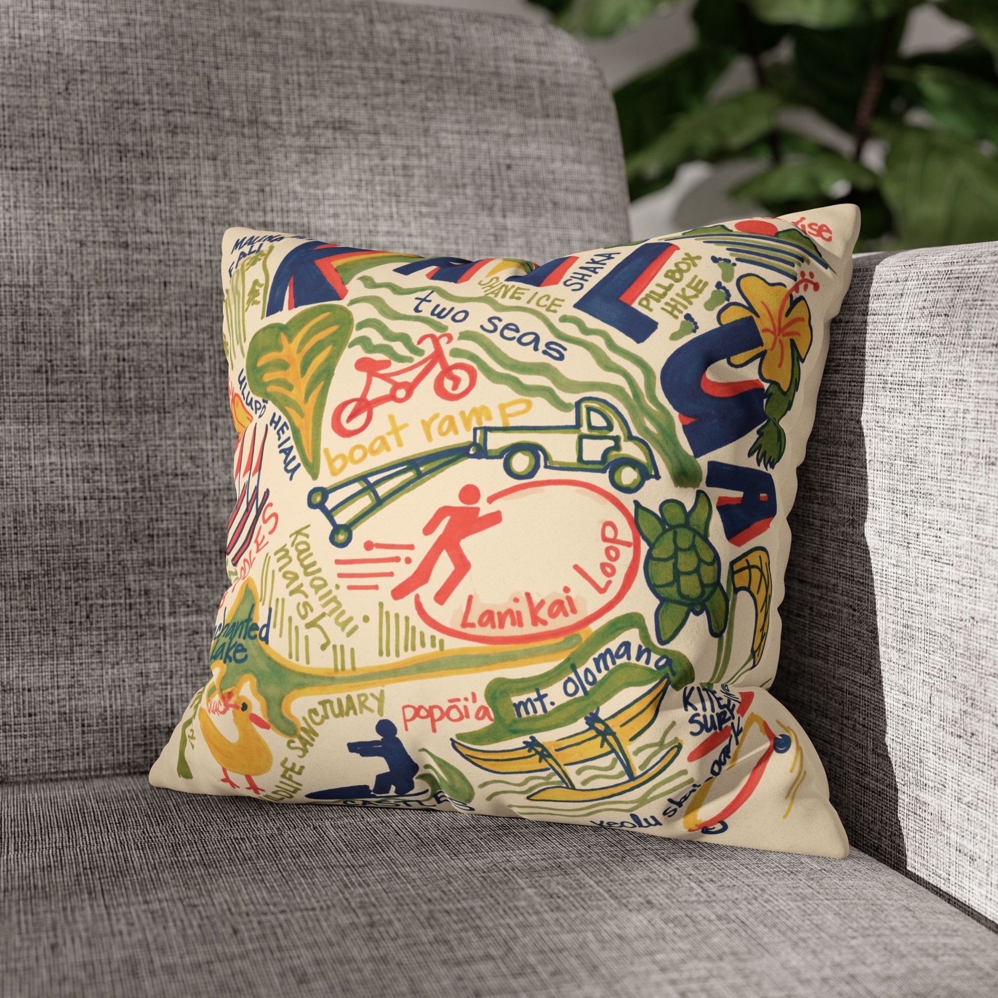 Decorative faux suede throw pillow cover featuring an original hand-drawn illustration of Kailua, Hawaii landmarks, beaches, surfing, paddling, turtles, and island icons on a gray couch.