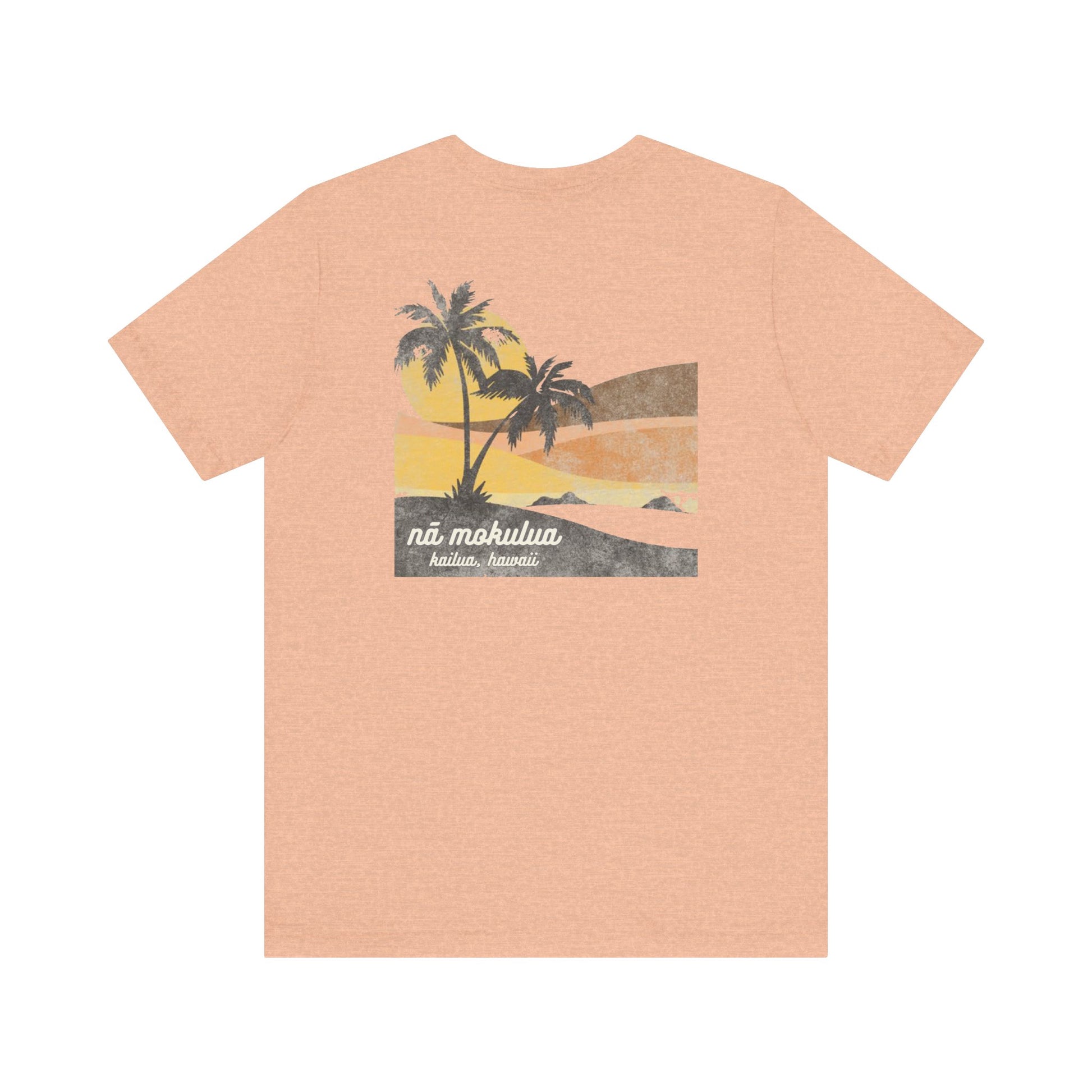 A heather peach short-sleeve t-shirt with a vintage-style graphic on the back depicting two palm trees against a yellow and orange sunset, with the text 'ná makulua' and 'Kailua, Hawaii!' printed below.