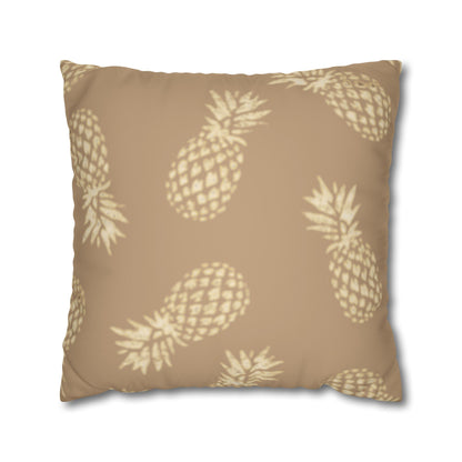 A square throw pillow in a warm tan color with a repeating cream pineapple pattern, shown against a plain white background.