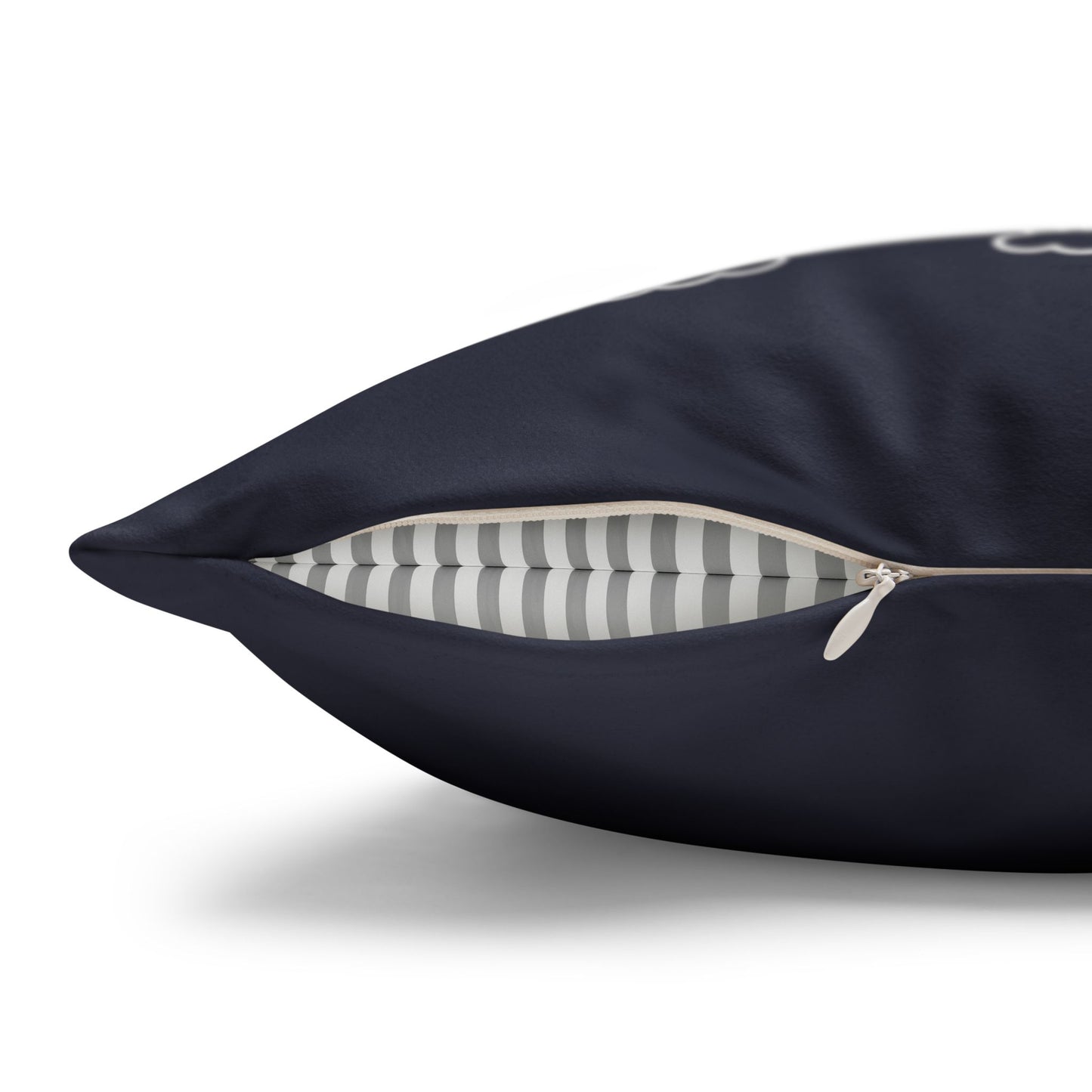 A close-up of a dark navy blue pillow with a partially unzipped corner, revealing a gray and white striped interior lining.