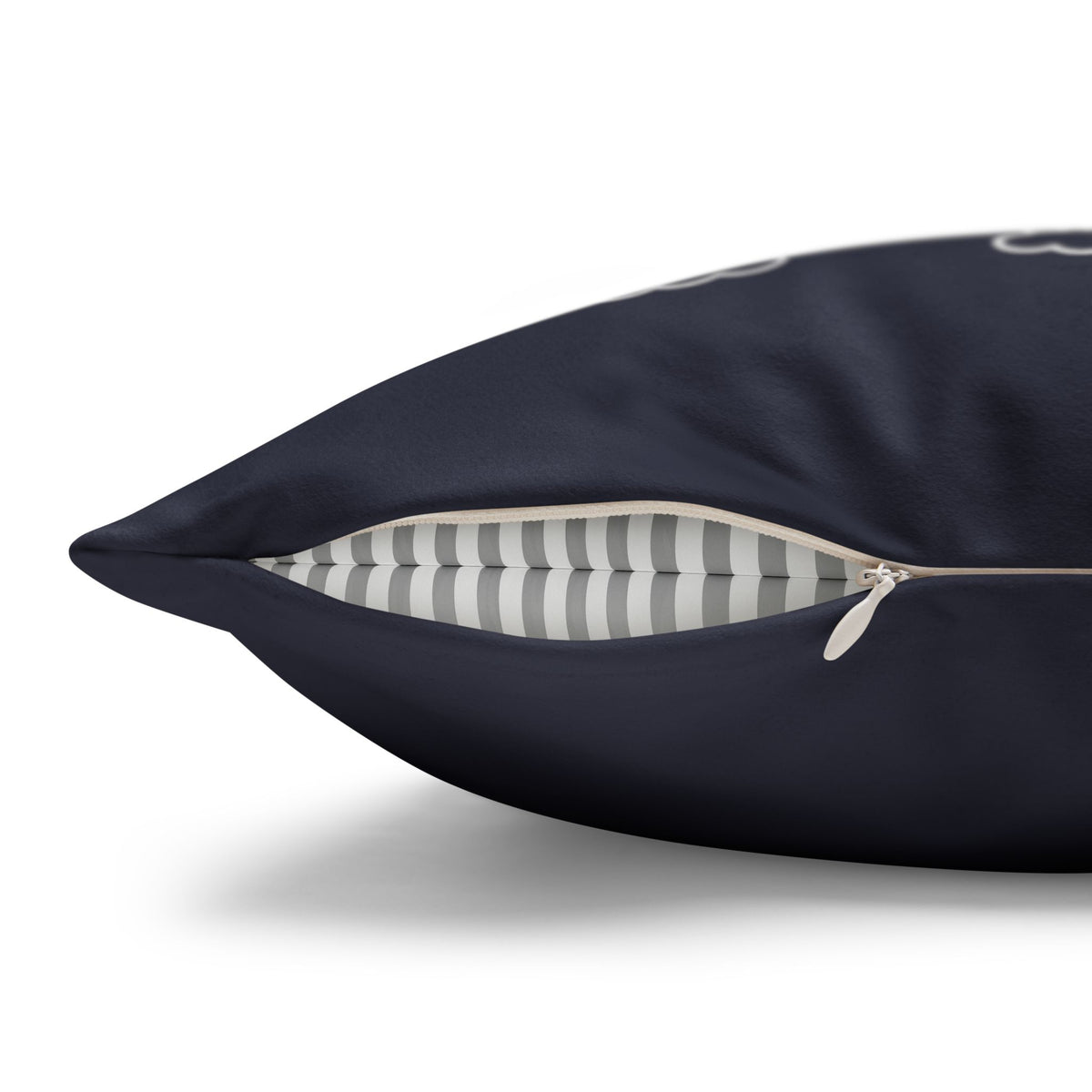 A close-up of a dark navy blue pillow with a partially unzipped corner, revealing a gray and white striped interior lining.