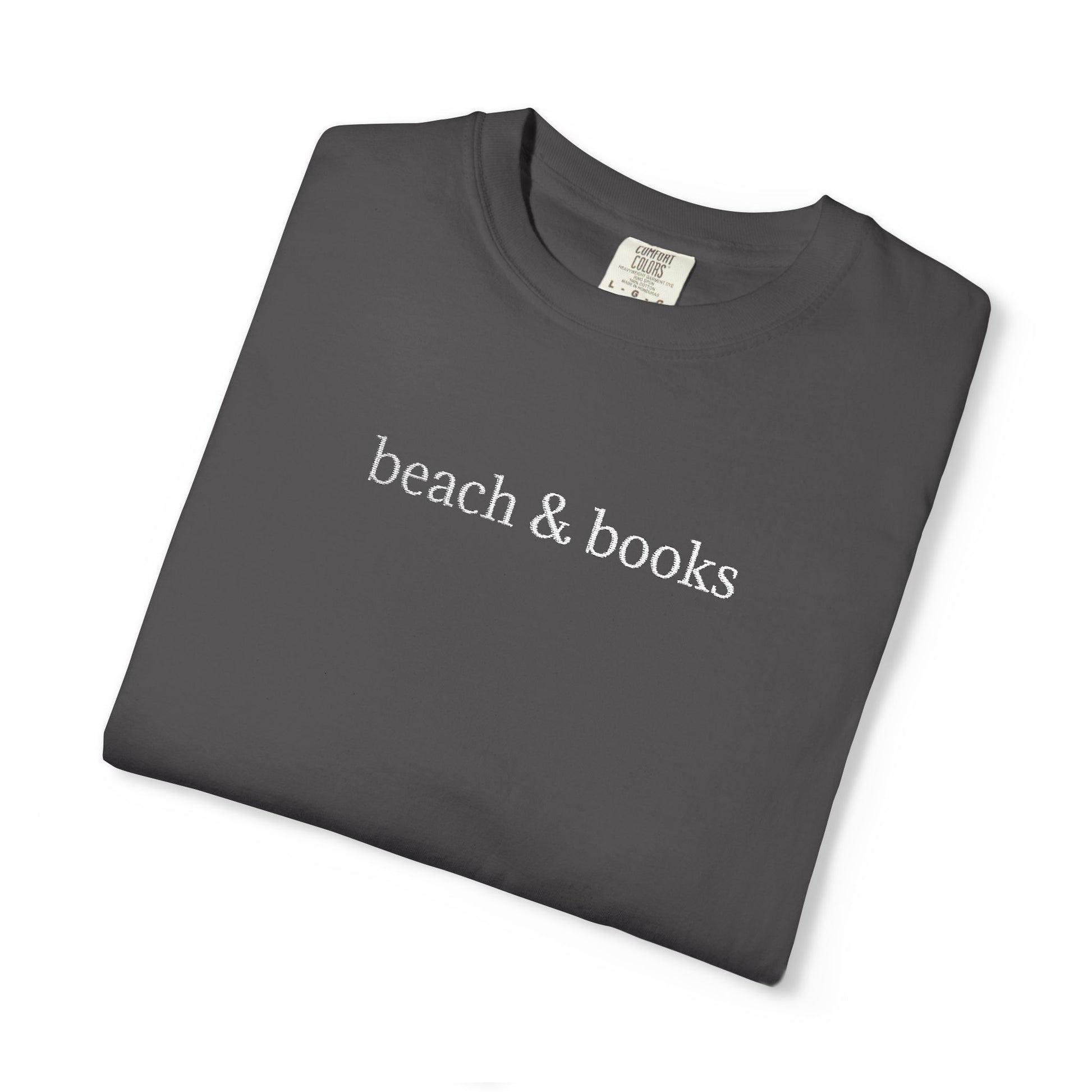 A folded grey comfort colors tee with 'beach & books' embroidered in white