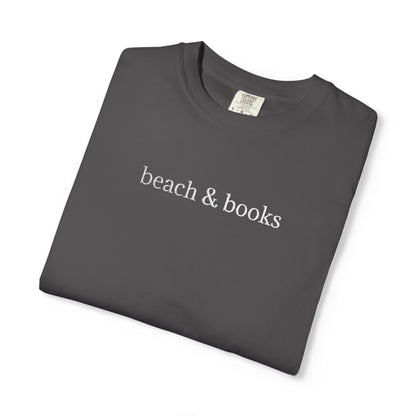 A folded grey comfort colors tee with 'beach & books' embroidered in white