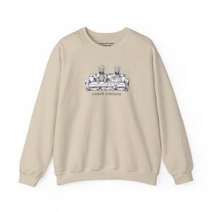 A beige crewneck sweatshirt featuring a black and white line art graphic of a couch with pineapples and the text 'couch cruisers' on the chest, displayed against a solid white background.