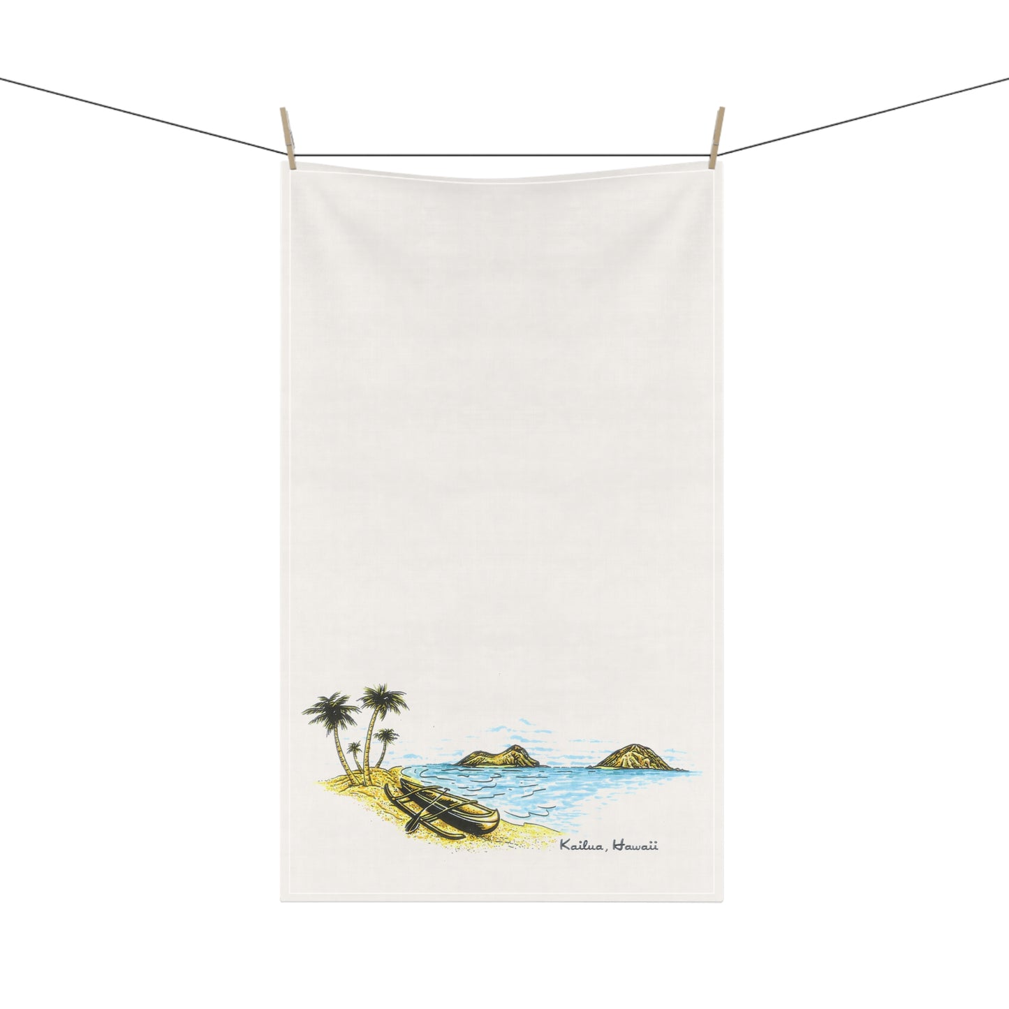 An off-white cotton tea towel with a hand-painted scenic illustration of Kailua Beach, Hawaii, hanging from a clothesline with wooden clips against a white background.