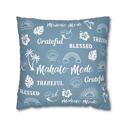 A square throw pillow in a dusty slate blue color, printed with white tropical-themed illustrations and words including 'Mahalo Mode', 'Grateful', 'Blessed', and 'Thankful'.