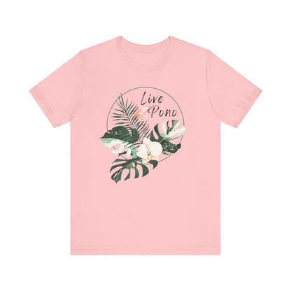A light pink short-sleeve crewneck t-shirt featuring a tropical graphic on the chest with green palm and monstera leaves, white flowers, and the words 'Live Pono' in a circular design.