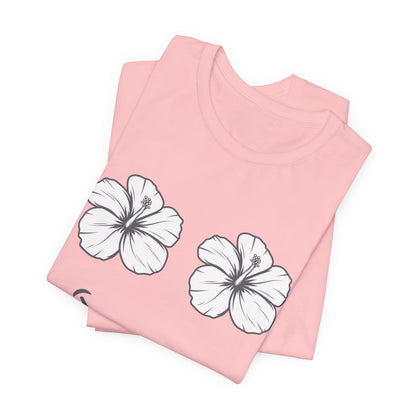 A folded light pink t-shirt with two white hibiscus flower graphics outlined in black, displayed on a clean white background.