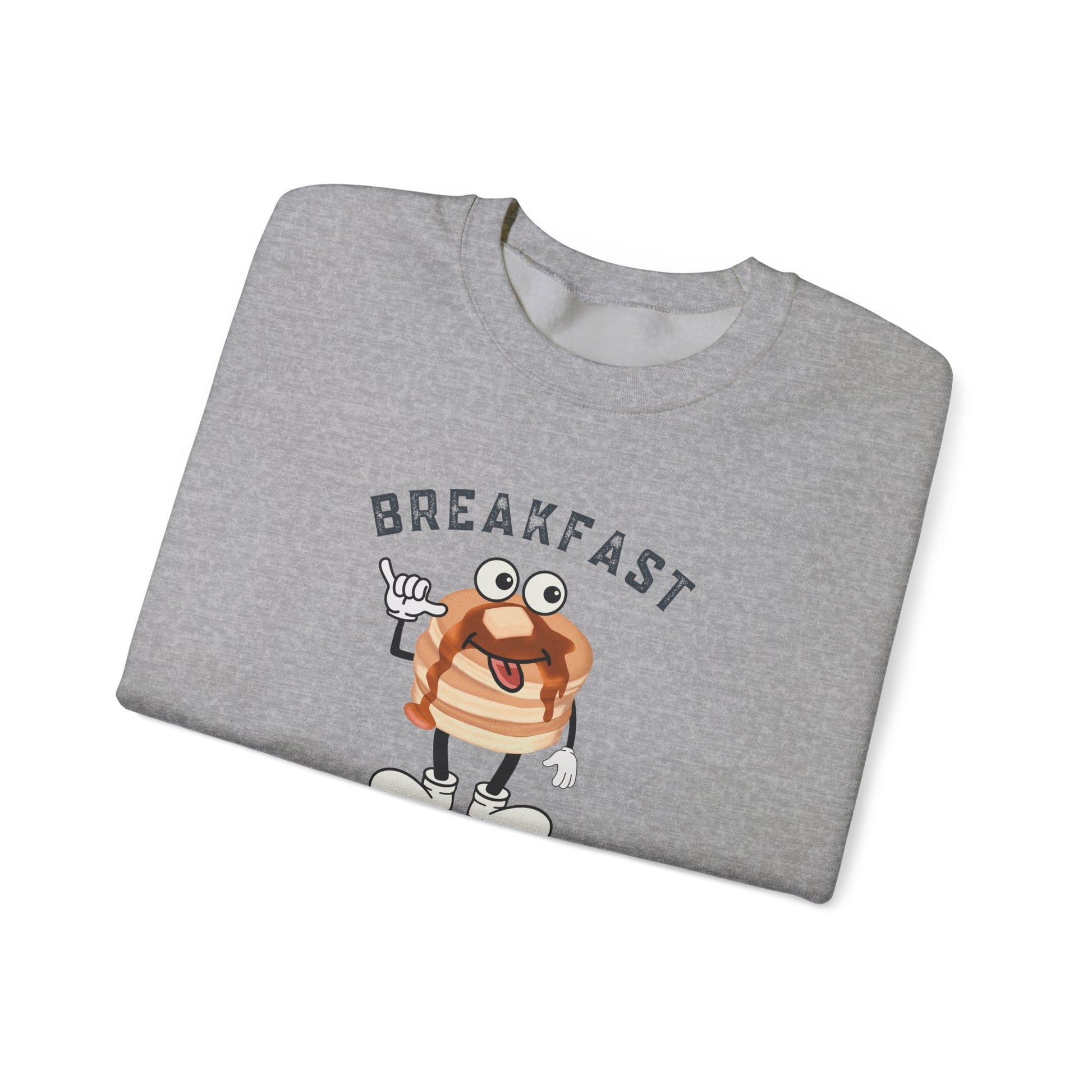 A folded heather gray crewneck sweatshirt featuring a cartoon character of a pancake with arms and legs, under the word 'BREAKFAST' in arched dark gray letters, shown on a plain white background.