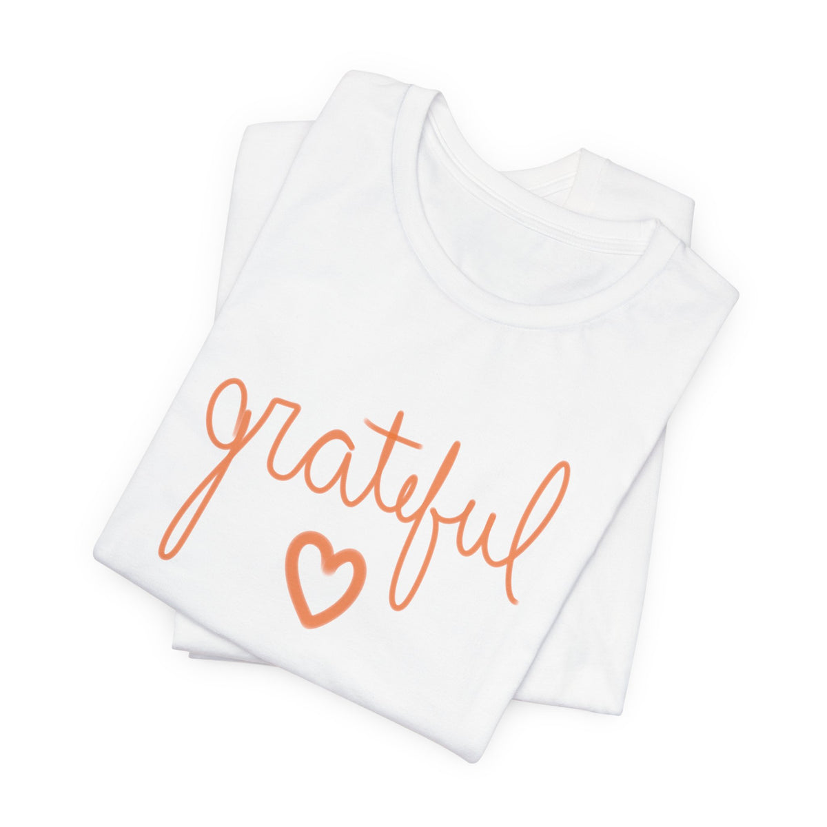 A folded white short-sleeve T-shirt with the word 'grateful' in orange cursive script and an orange heart outline on the front, shown on a clean white background.