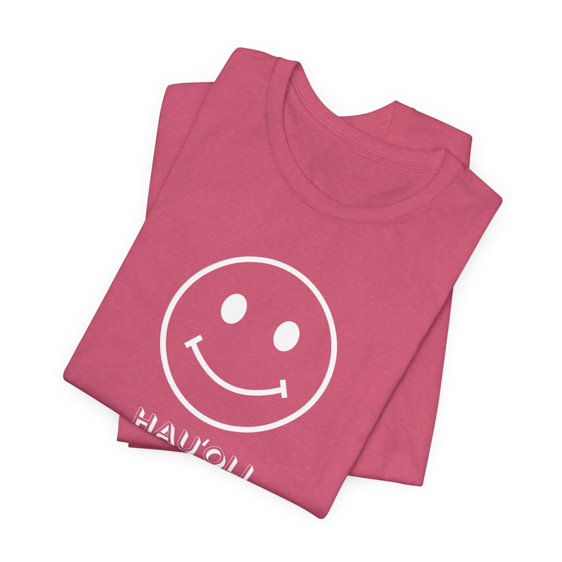 A folded dusty rose pink t-shirt featuring a white smiley face graphic and the word 'HAWAII' printed in white below it, set against a plain white background.