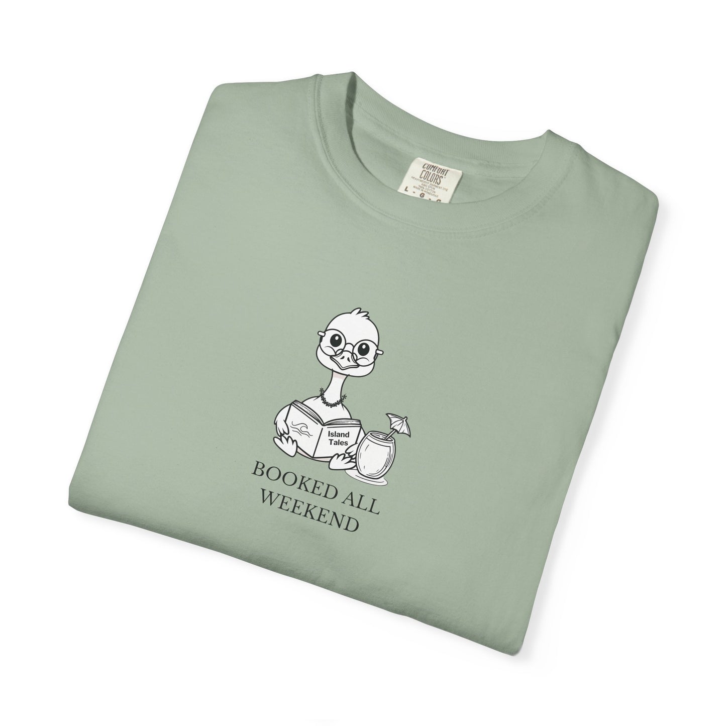 A light green comfort colors t-shirt with design of a nene goose reading a book and text 'booked all weekend' folded
