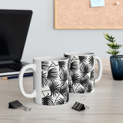 Two Palm Fan Black coffee mugs with black and white tropical palm print by Global Village Kailua sitting on a desk with a computer and binder clips.