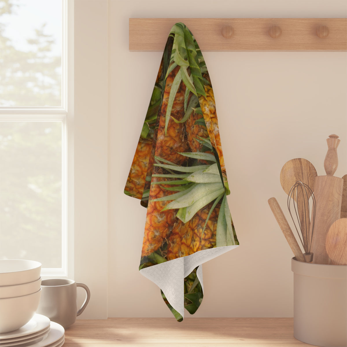 Pineapple Pile kitchen towel with tropical pineapple print by Global Village Kailua hanging on a wooden peg in a kitchen setting