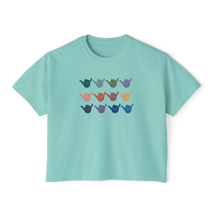 A light teal crop short-sleeve t-shirt with a graphic of twelve shaka signs in various colors arranged in three rows, displayed on a clean white background.