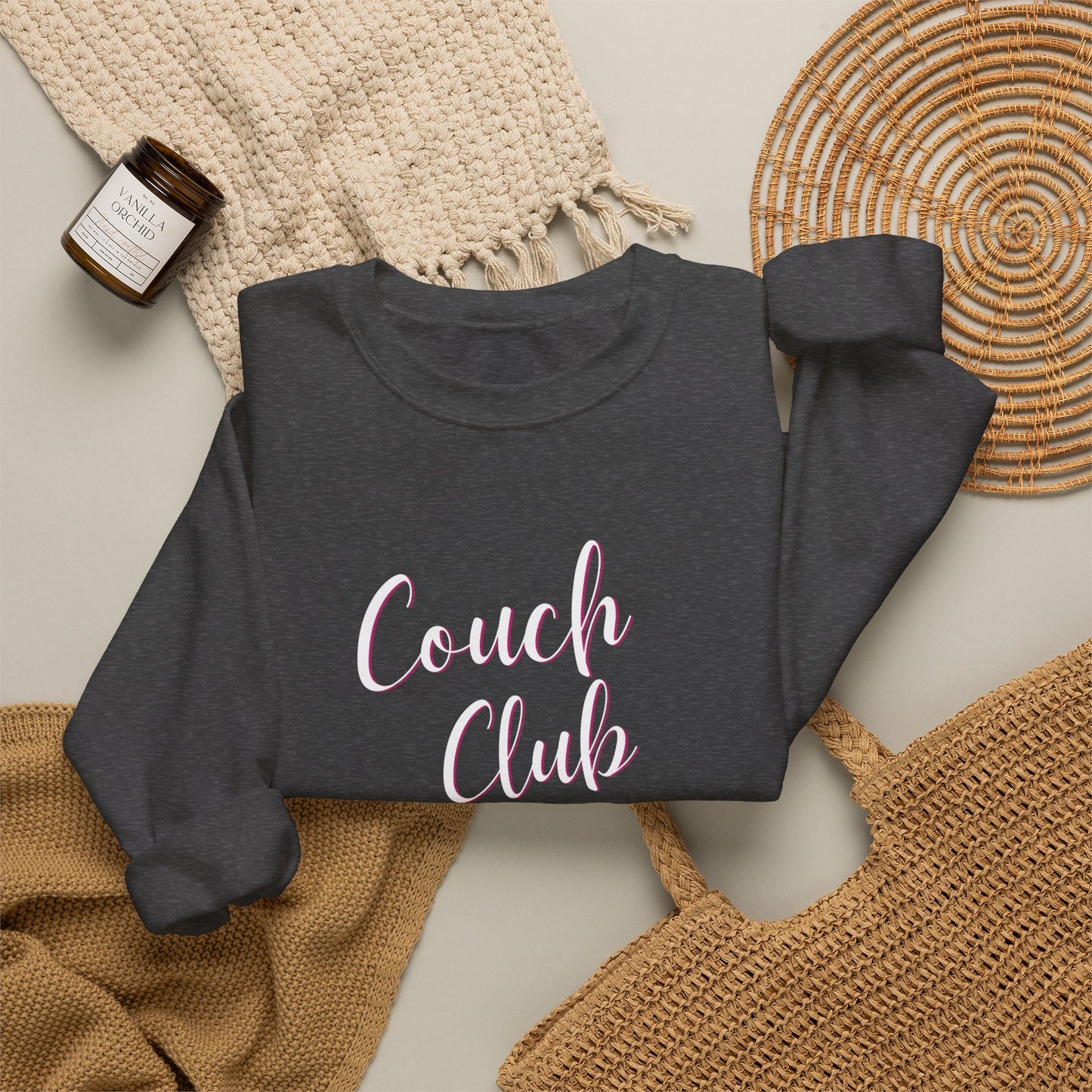 Folded dark gray sweatshirt with a graphic design text 'Couch Club' on a textured surface