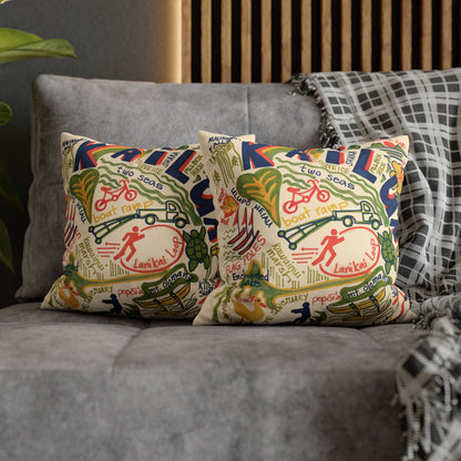 Two decorative throw pillows with a colorful vintage-style map and bicycle illustration pattern of Kailua, Oahu styled on a gray fabric sofa with a plaid throw blanket.