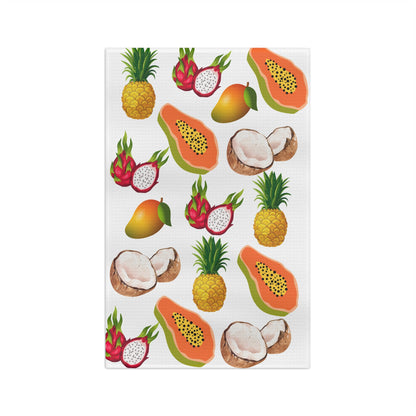 A white rectangular kitchen towel featuring a colorful repeating pattern of tropical fruits, including papayas, pineapples, mangoes, dragon fruit, coconuts, and a whole mango, shown on a plain white background.