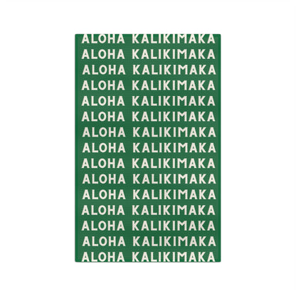 Green Aloha Kalikimaka holiday kitchen towel with repeating cream lettering