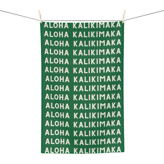 Green Aloha Kalikimaka holiday kitchen towel with repeating cream lettering