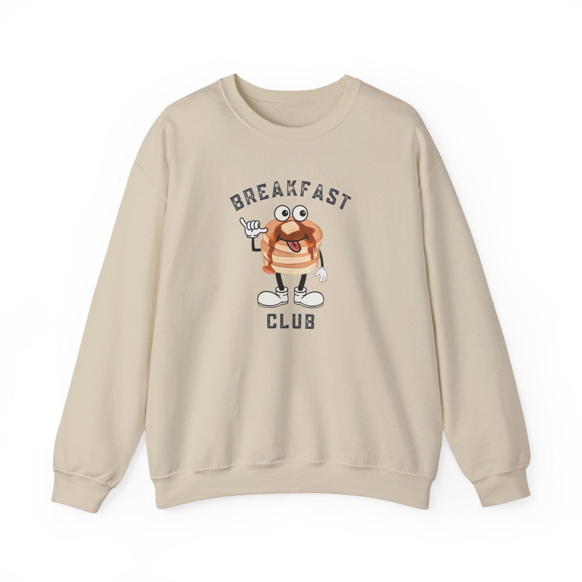 A sand crewneck sweatshirt featuring a cartoon graphic of a breakfast stack of pancakes character with the text 'BREAKFAST CLUB' printed on the front, displayed against a clean white background.
