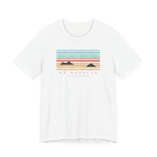 A white short-sleeve crewneck t-shirt featuring a colorful graphic print of a sunset over mountains with the text 'NÁ MOKULUA' and 'KAILUA, HAWAII' printed below.